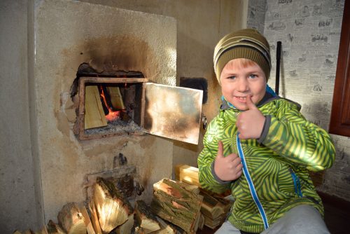 Rinatmaakylän pieni poika iloitsee  uunin lämmöstä. Ukrainanhätä toimittaa myös polttopuita tilauksesta.